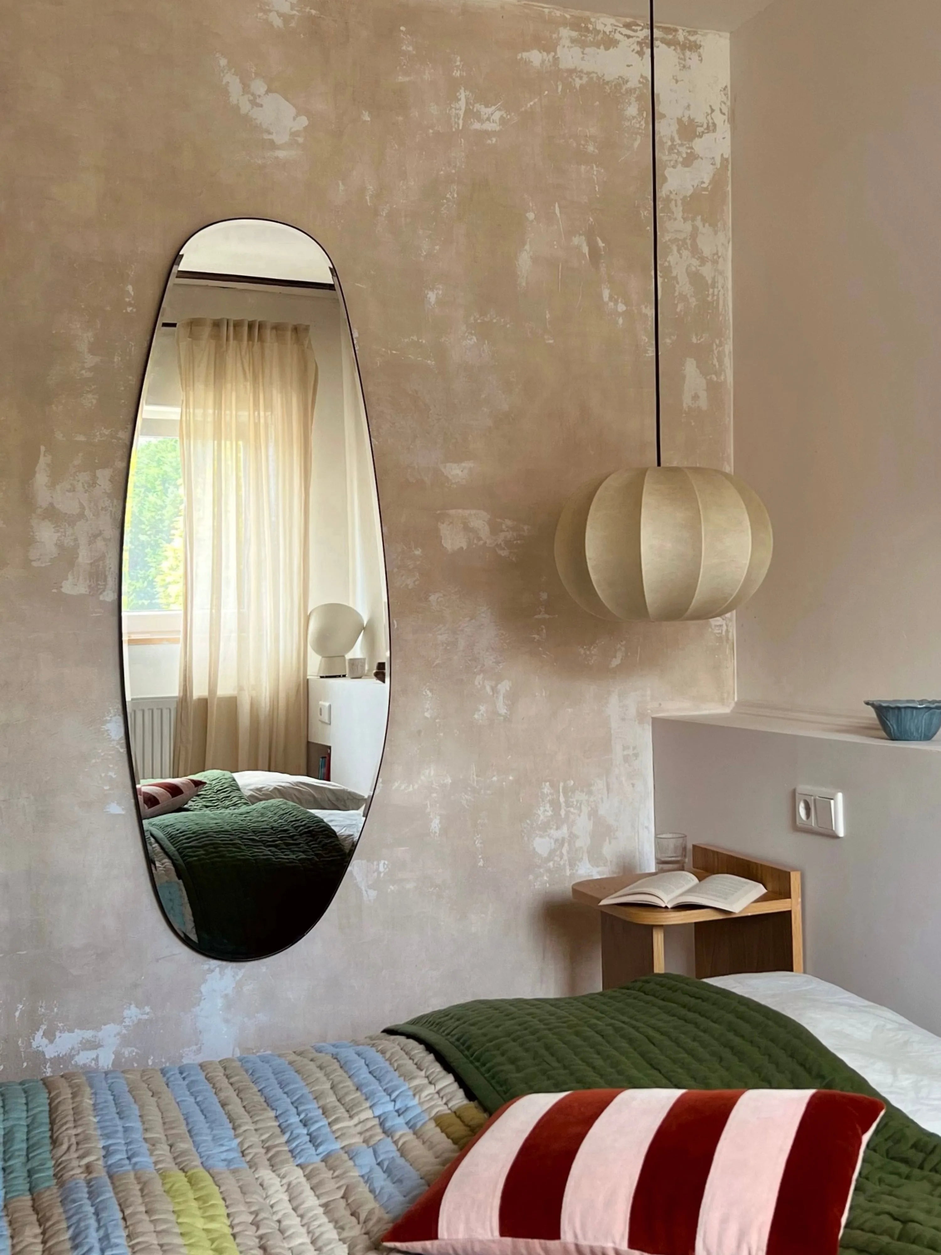 Asymmetrical Opal Mirror Large reflecting a bright, minimalist interior