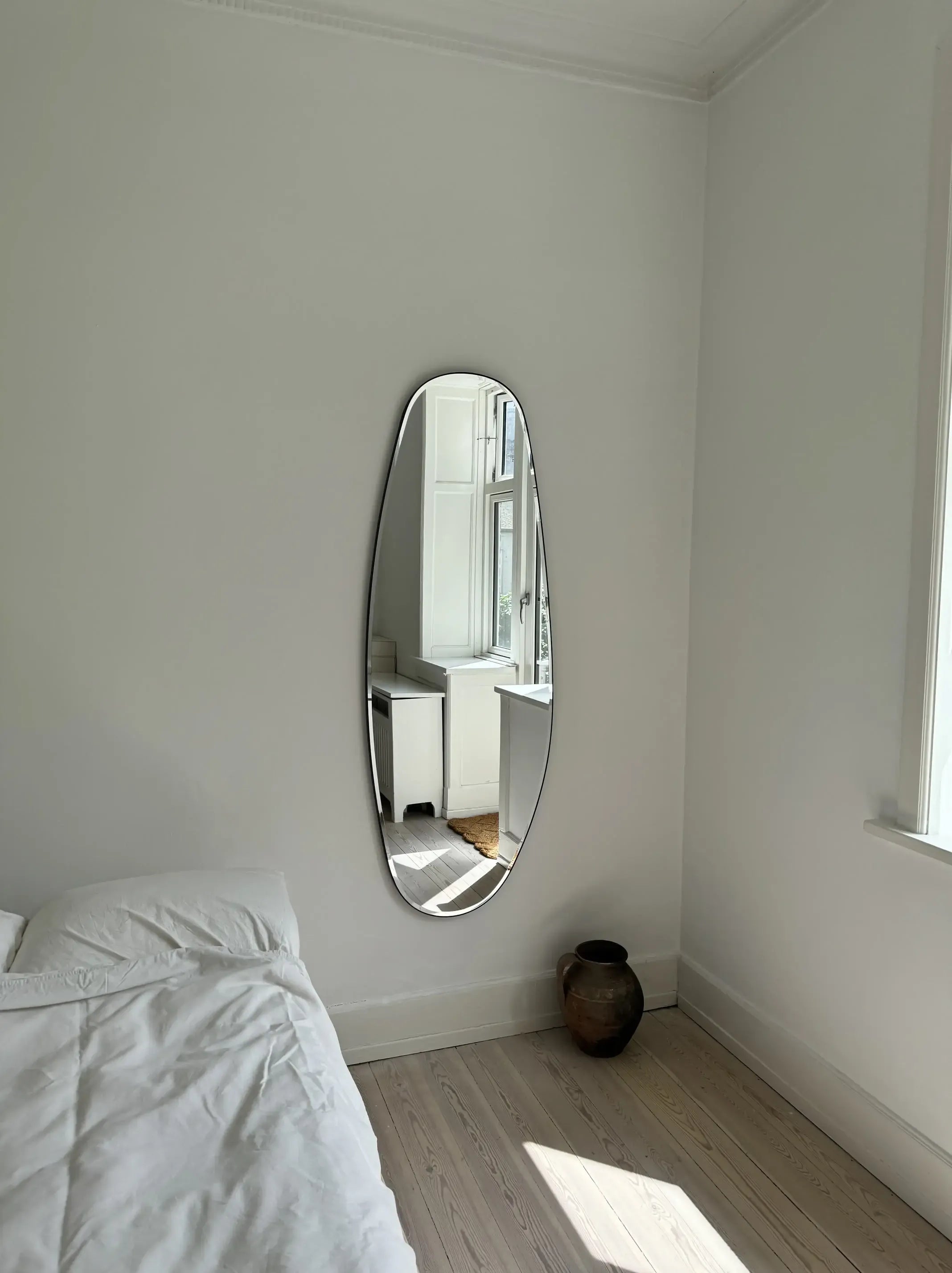 Opal Mirror Large in bedside with a bronze vase below it