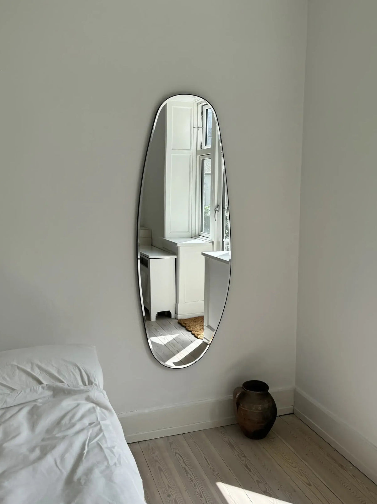 Opal Mirror Large in bedside with a bronze vase below it
