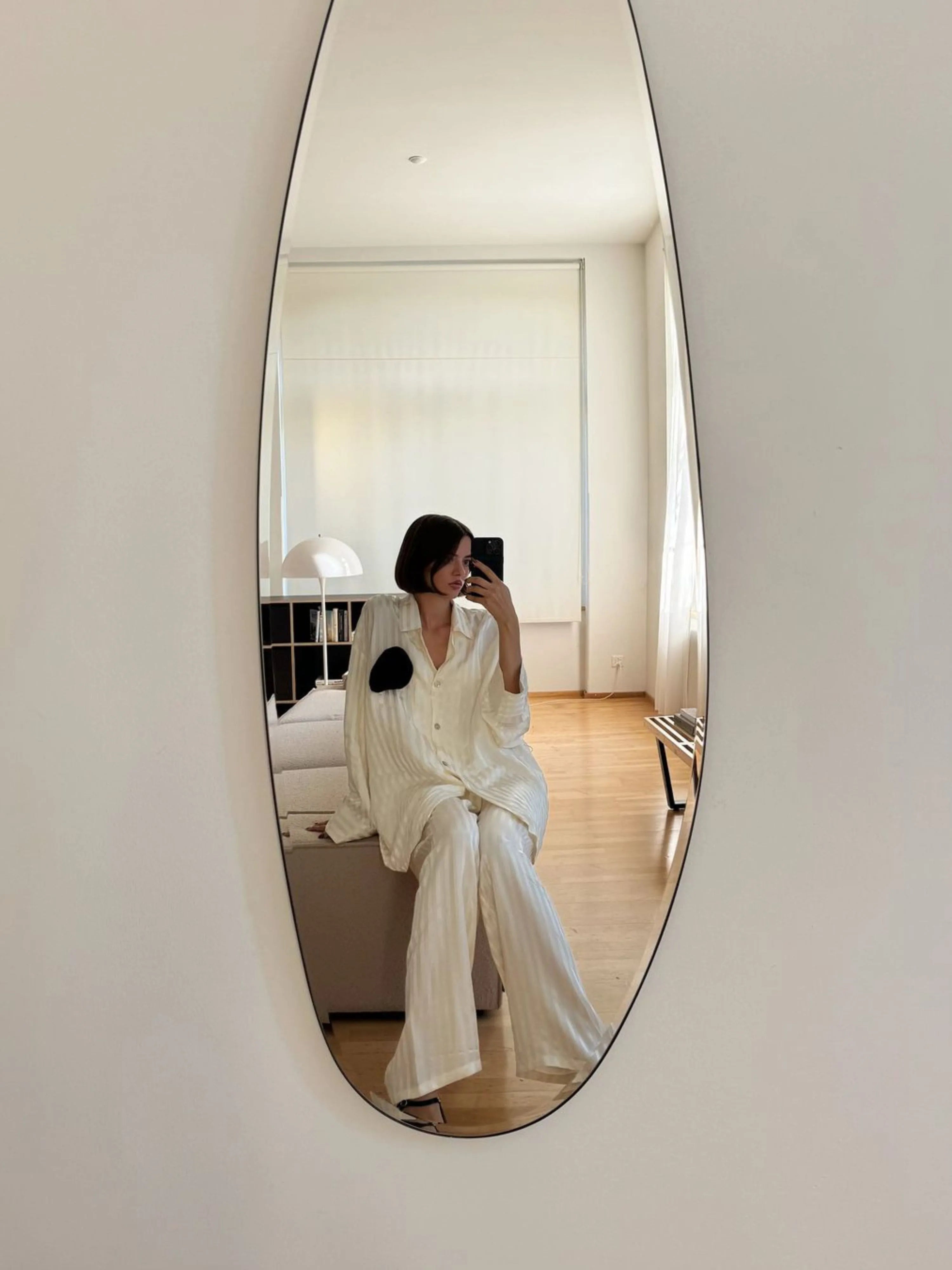 Opal Mirror Large showing model in reflection sitting on couch